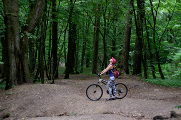 Fototapeta na wymiar young girl in sport wear with bicycle riding in forest in summer