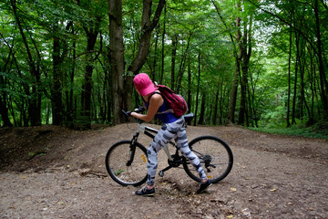 Fototapeta na wymiar young girl in sport wear with bicycle riding in forest in summer