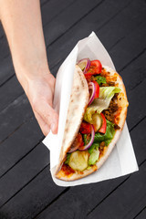 Hand with street food stromboli, calzone on a black background