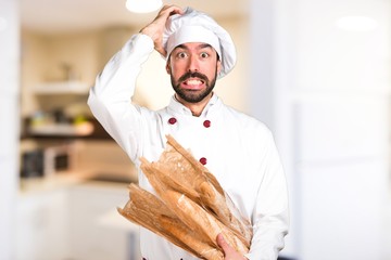 Frustrated young baker holding some bread in the kitchen