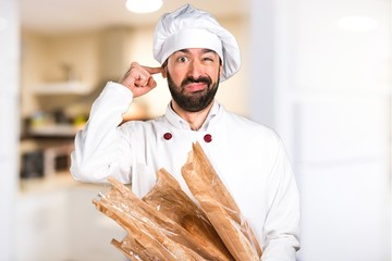 Young baker holding some bread and covering his ears in the kitchen