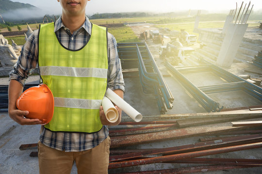 Engineer Or Safety Officer Holding Hard Hat With Blueprint On Building Construction Site