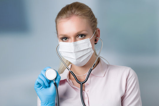 Junge Ärztin oder Studentin mit Mundschutz und Stethoskop