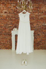 Beautiful wedding dress hang on in front of brick wall
