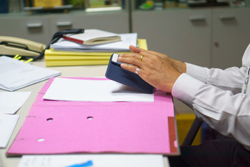 close up businessman using smartphone with business document paper for signed on the table in the office.