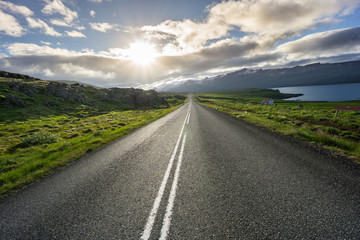 Fototapeta na wymiar Iceland - Magic moment over straight highway between green fields next to fjord