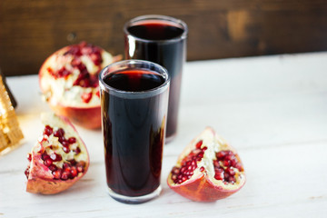 Pomegranate juice in glass surrounded by pomegranate halves.