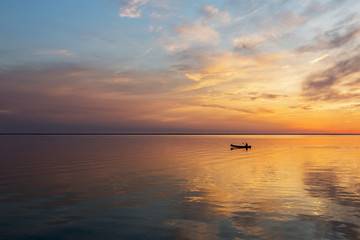 Naklejka na ściany i meble Paddling canoe at sunset