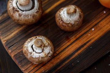 Mushrooms on board with fresh vegetables on background.
