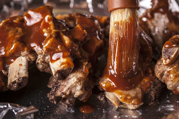 Putting sauce on ribs.