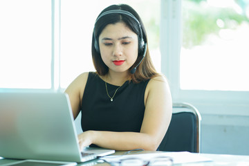 close up focus on asian call centre woman with headphone trying to response answer or working in operation office room.helpdesk hotline concept.