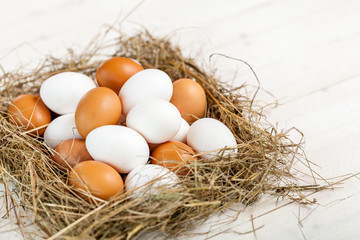Fresh country eggs with straw on rustic wooden white table
