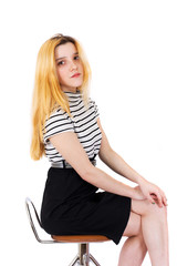 Young attractive blonde girl sitting on bar stool white background