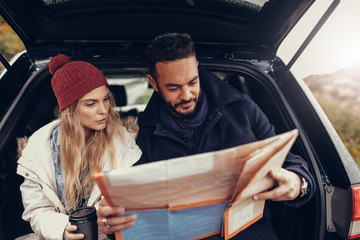 Young couple using map on a road trip © Jacob Lund