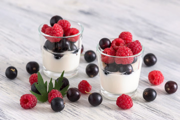 Yogurt in glasses with fresh berries. Berries of currants and raspberries.