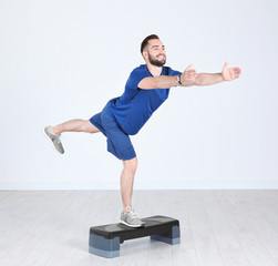 Young sporty man training legs with stepper in gym
