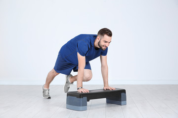 Obraz premium Young sporty man training legs with stepper in gym