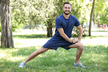 Sporty young man doing sport exercises for legs in park