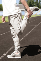Obraz premium Young man stretching quadriceps on running track, fitness and exercise routine, athletic training and sports warm-up
