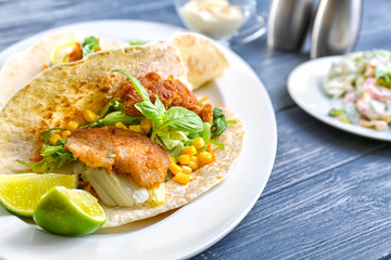 Delicious fish taco on white plate on blue dark table