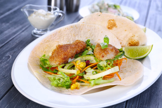 Delicious fish tacos on white plate on table