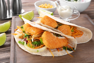Delicious fish tacos on board on wooden background