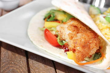 Delicious fish taco served on white plate on wooden table