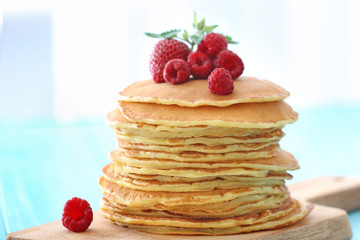 Delicious pancakes with raspberry and strawberry on wooden board