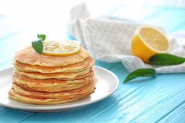Plate with delicious pancakes and lemon on table