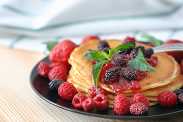 Plate with delicious pancakes on table