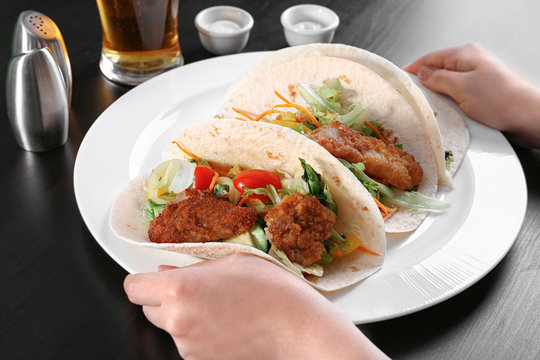 Hands holding plate with delicious fish tacos