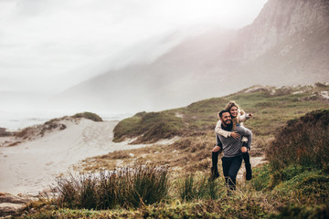 Man giving woman piggyback on winter beach