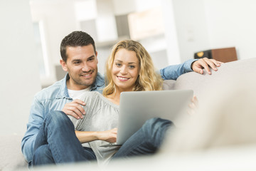 Happy young couple watching internet on their laptop