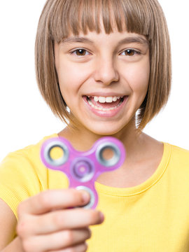 Young girl holding popular fidget spinner toy - close up portrait. Happy smiling child playing with Spinner, isolated on white background.