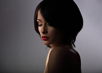 Beautiful makeup woman with thinking sad looking down and short hair style, red lipstick on dark...