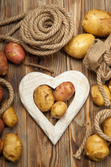 Potatoes and heart on a wooden background