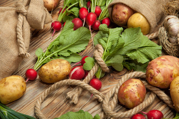 Potatoes and radishes on a wooden background