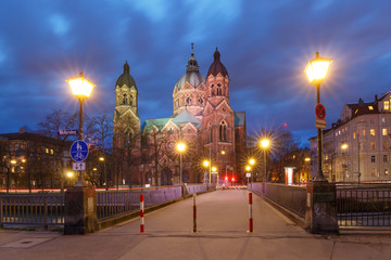 Fototapeta premium Saint Lucas Church, the largest Protestant church in Munich, and bridge across Isar River at night, Bavaria, Germany