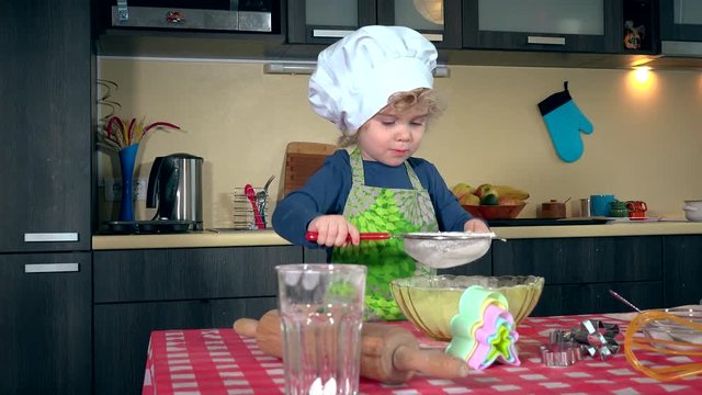 Cute little girl sifting flour for cake on kitchen table