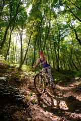 young girl in sport wear with bicycle riding in forest in summer