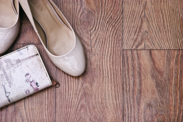 Beige women's shoes with a purse on a wooden background