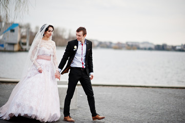 Naklejka na ściany i meble Newly married couple walking and posing on the lakeside on their wedding day.