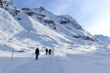 Fototapeta na wymiar Group of people hiking on wintery snowy path and mountain panorama in Stubai Alps, Austria