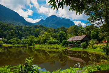 Traditional wooden house near the lake and mountain in the background. Kuching to Sarawak Culture village. Borneo, Malaysia