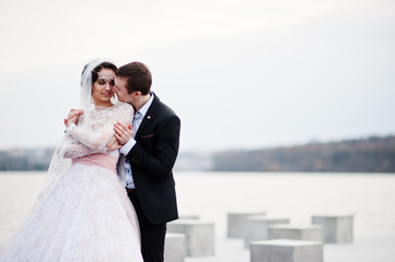 Newly married couple walking and posing on the lakeside on their wedding day.