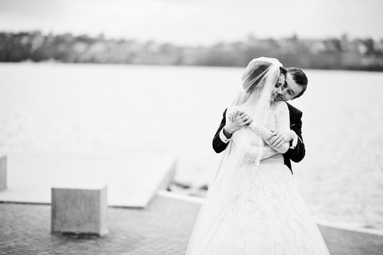 Newly married couple walking and posing on the lakeside on their wedding day. Black and white photo.
