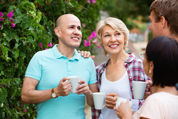 Mature couples walking and drinking coffee on holiday