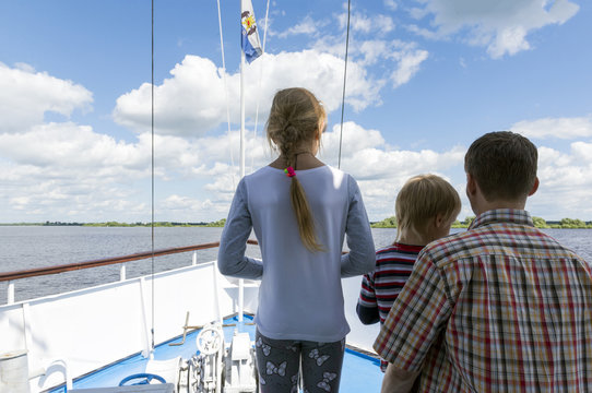 man, a father with two children, a boy and a girl on the deck of the ship on the river