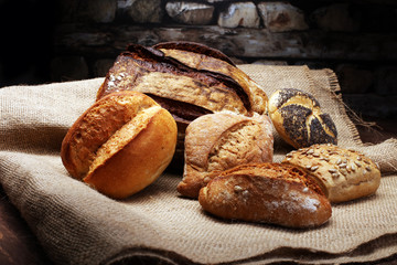Different kinds of bread and bread rolls on wooden table