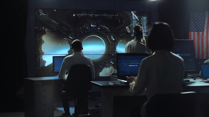 Back view of people working and managing flight in mission control center. Landing of spaceship on Moon.